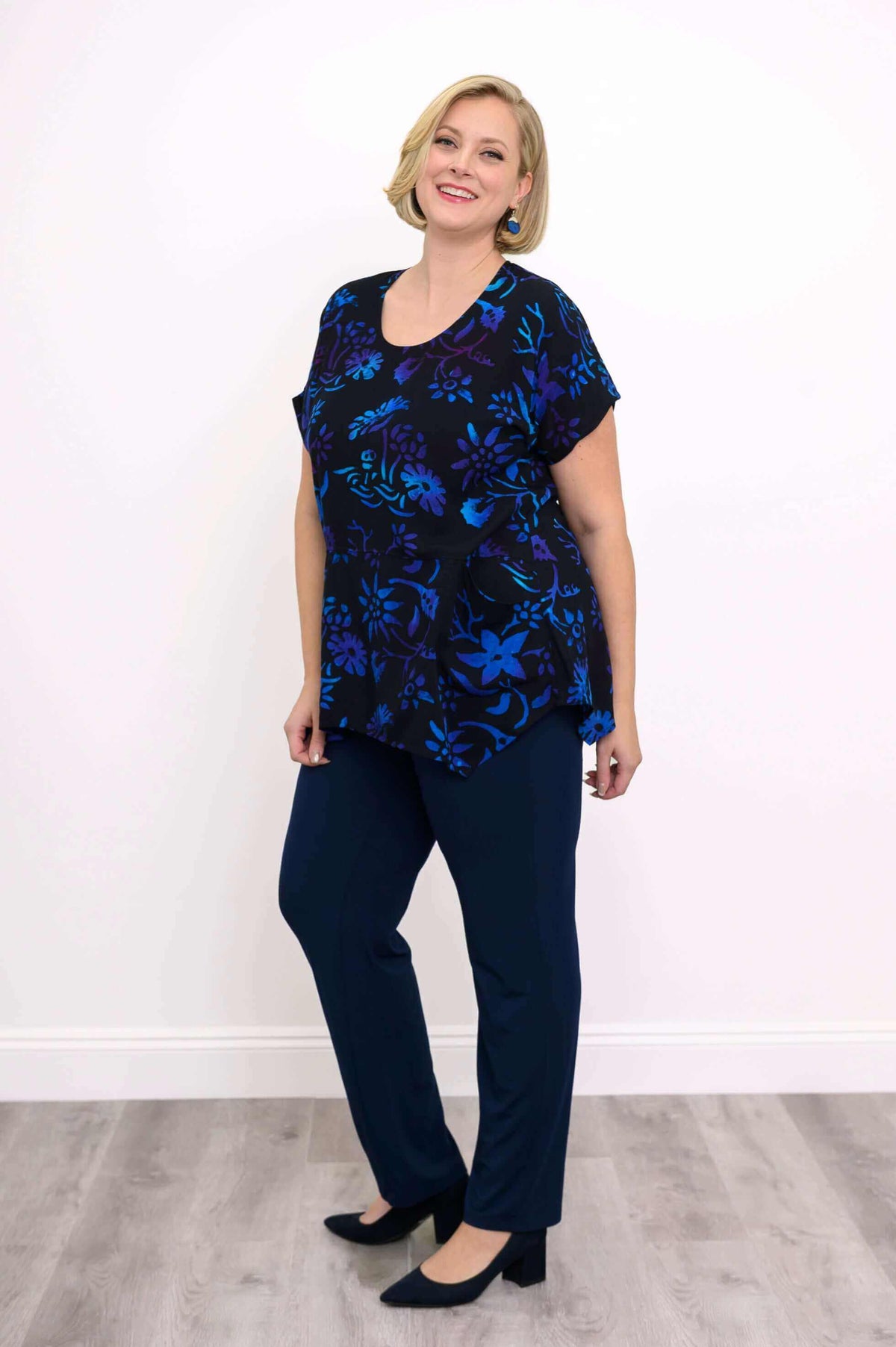 Woman modeling black plus size top with blue and purple flower pattern and pockets