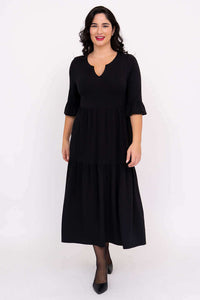 Model wearing a black tiered midi dress with keyhole neckline and ruffle sleeves