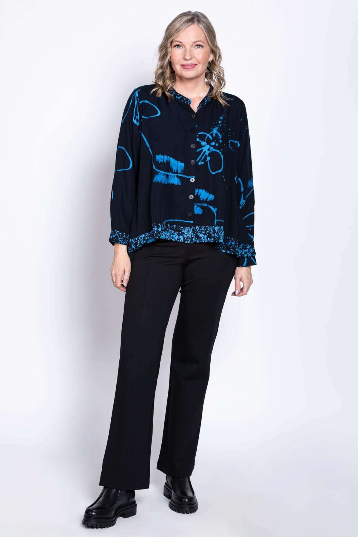 Woman modeling blue Batik print blouse, standing against a white background