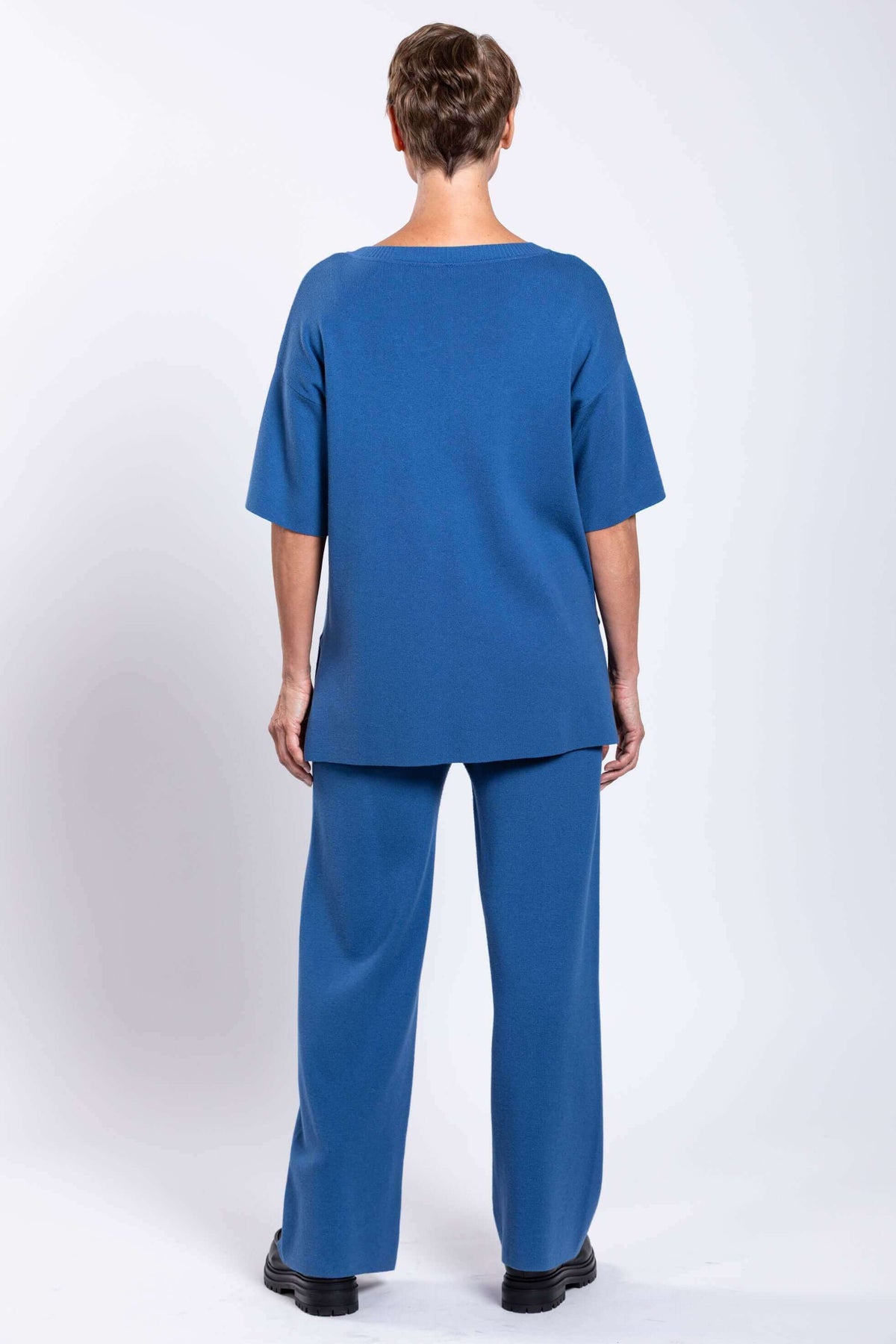 Model in blue relaxed-fit top and straight-leg pants, back view