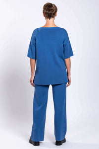 Model in blue relaxed-fit top and straight-leg pants, back view