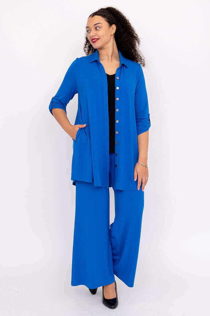 Model wearing blue wide-leg pants with matching shirt, hands in pockets