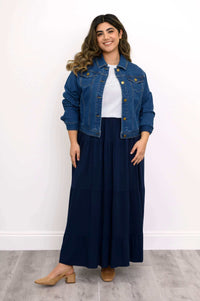 Model wearing denim jacket and navy  tiered maxi skirt, standing and smiling