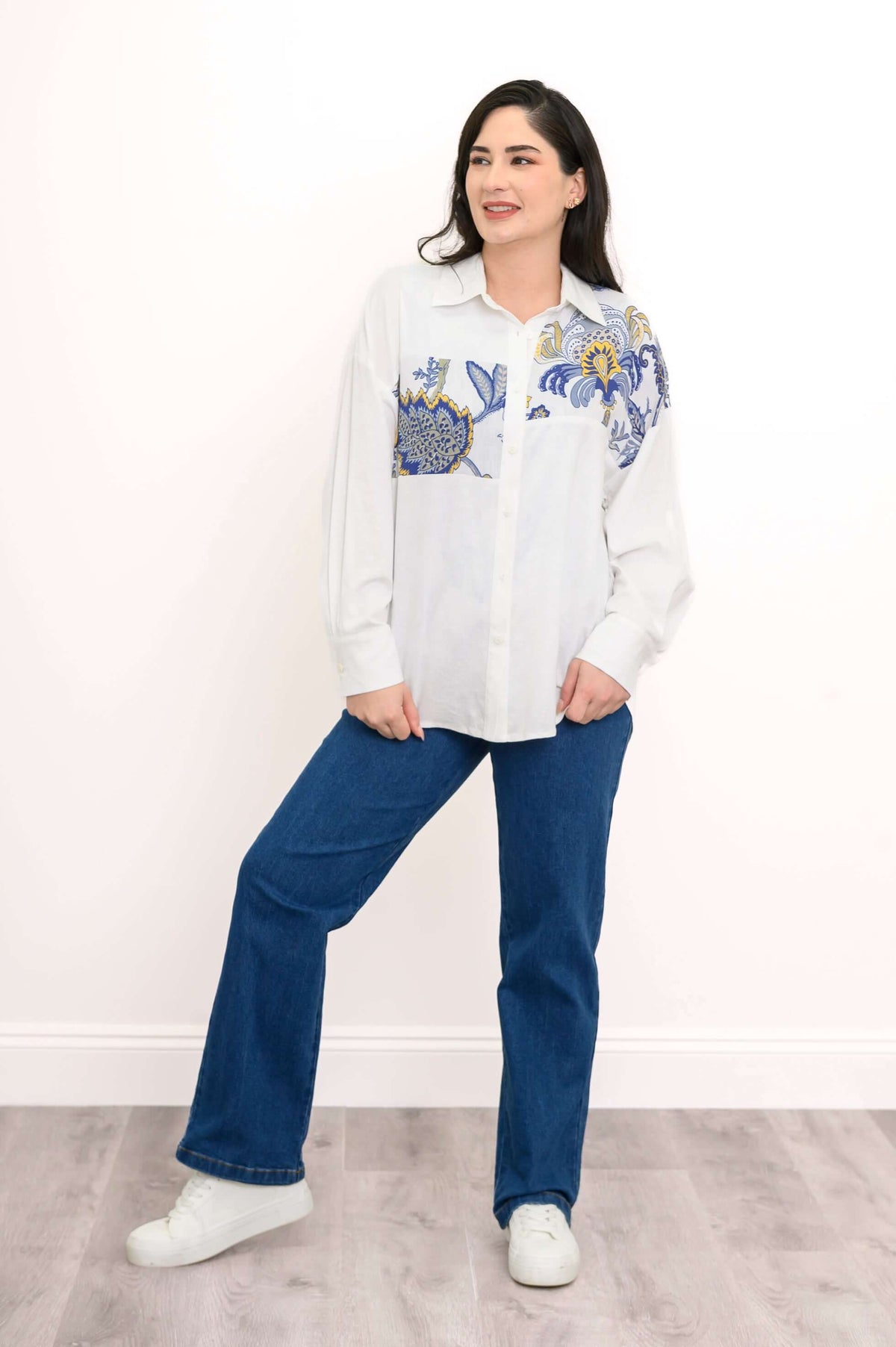 Model wearing full outfit with white print blouse and blue jeans