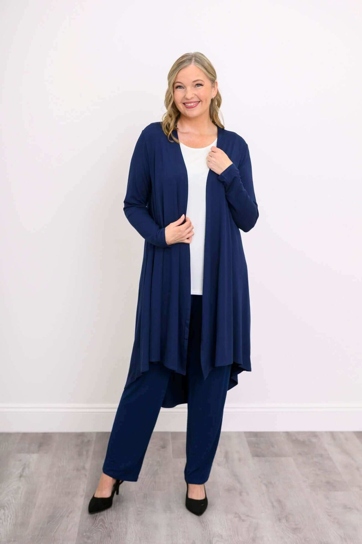 Model wearing navy blue open front long sleeve duster cardigan over white top and matching pants