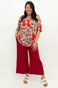 Model posing in a red patchwork print blouse paired with red wide-leg pants