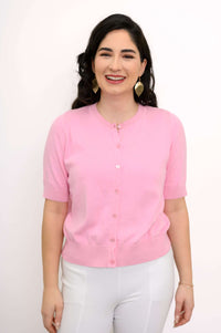 Model wearing a pink short-sleeve cardigan with white pants