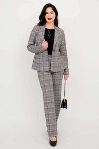 Model wearing a plaid suit set with trousers and blazer, holding a bag