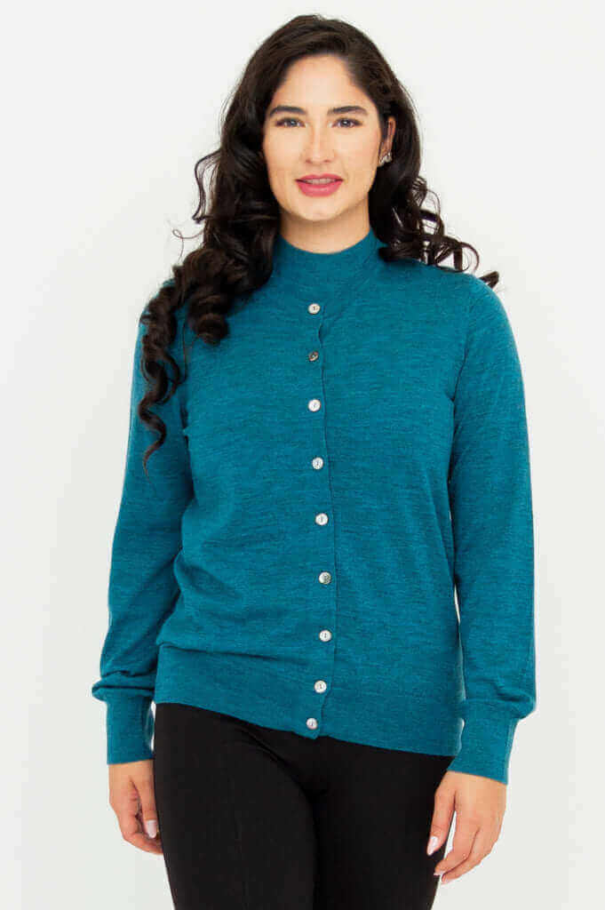 Front view of a woman wearing a soft teal merino wool button up cardigan sweater in studio.