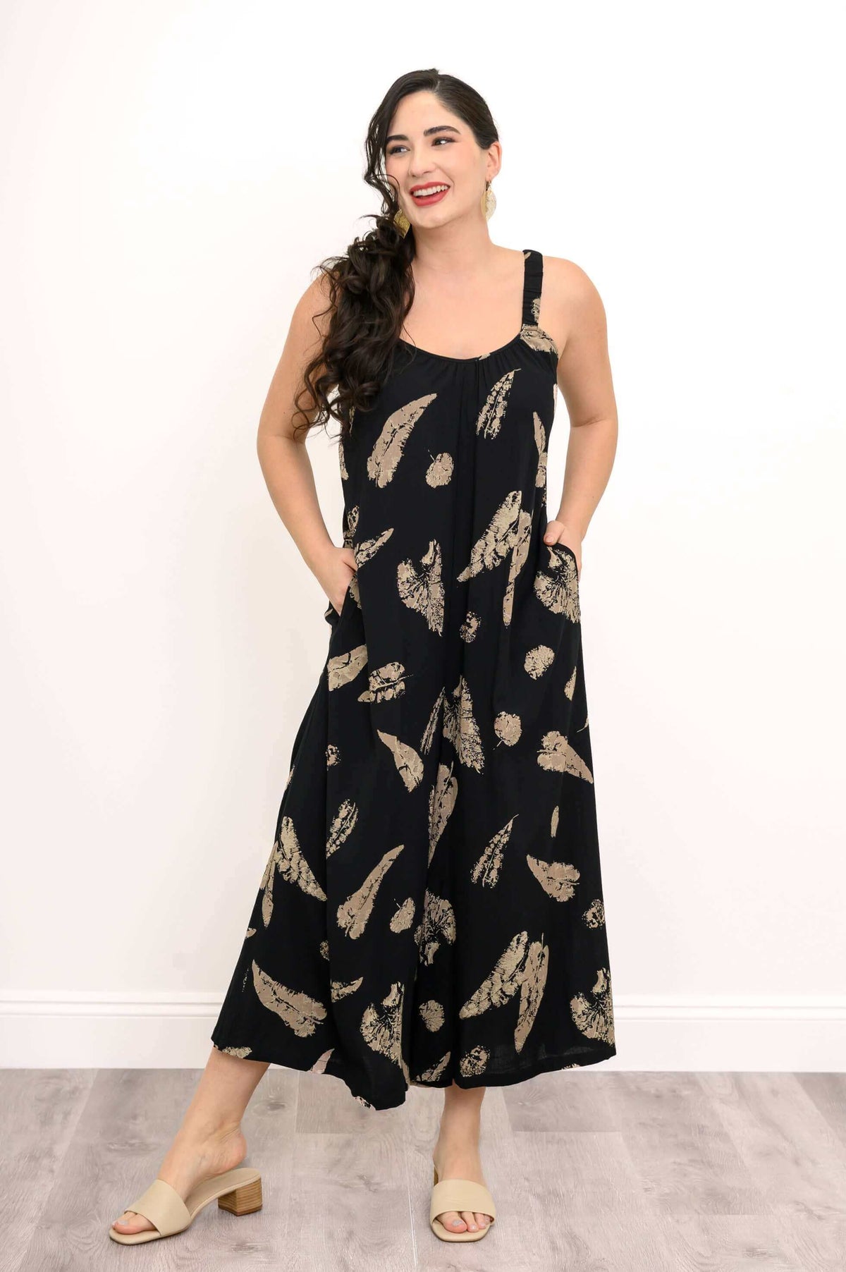Model smiling in wide-leg black jumpsuit with tan abstract print