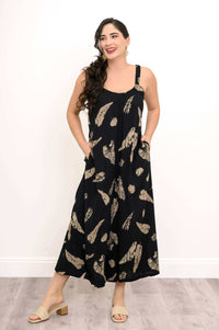 Model smiling in wide-leg black jumpsuit with tan abstract print