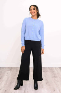 Woman modeling a light blue cashmere cardigan paired with black trousers and heeled boots
