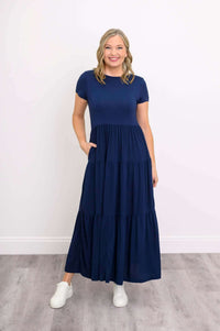 Model with hand in pocket wearing navy blue tiered maxi dress