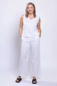 Model standing with hands in pockets wearing Parker Pant in white striped linen-blend