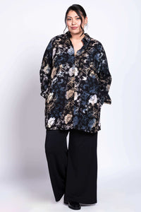 Model with hands in pockets wearing black floral batik print tunic shirt