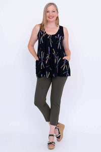 Woman posing with hands in pockets, wearing black pleated dragonfly print tank and olive pants