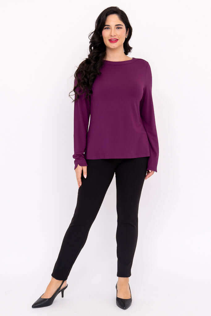Woman modeling purple boat neck top with arms relaxed