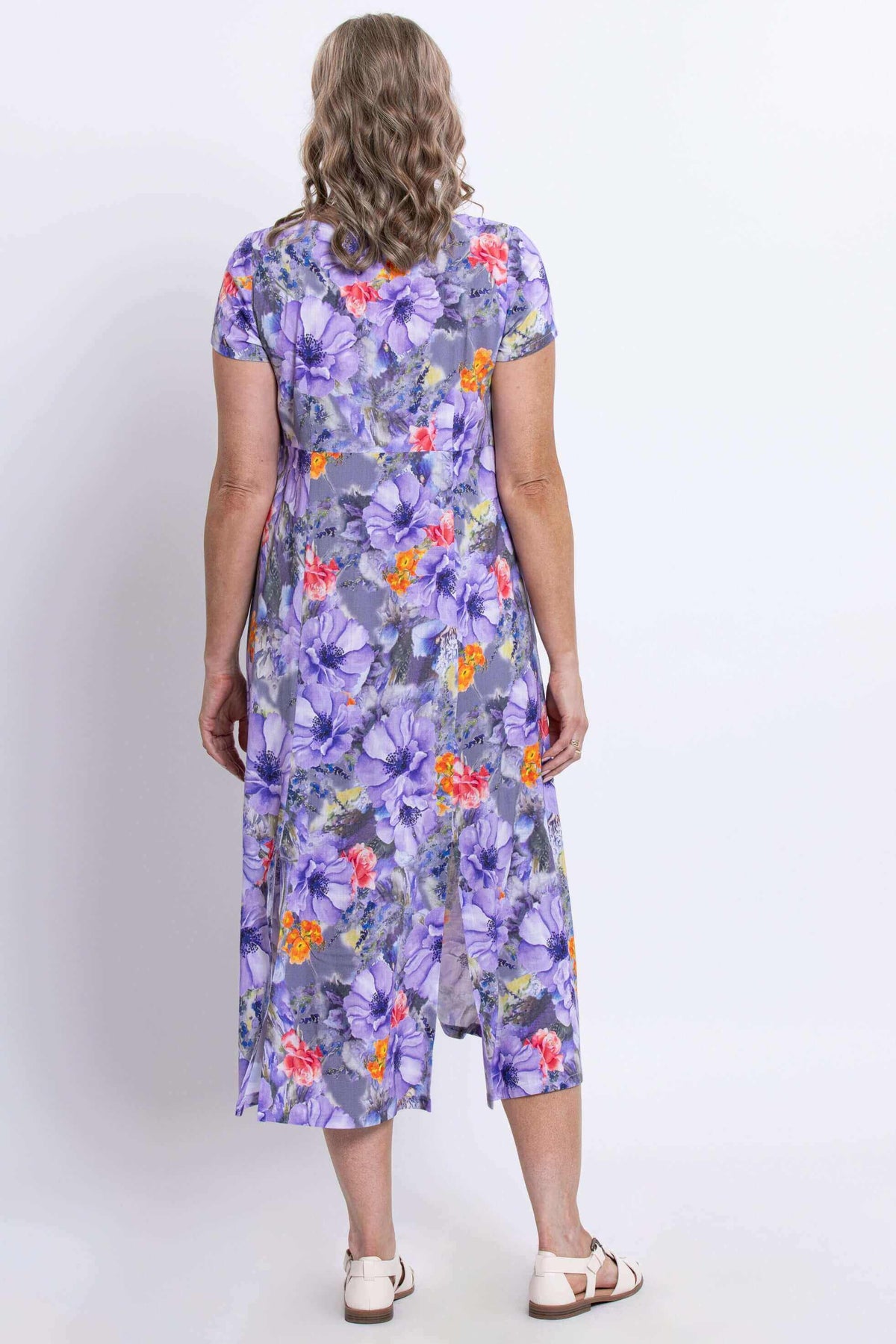 Back view of woman wearing a purple floral dress with back slit