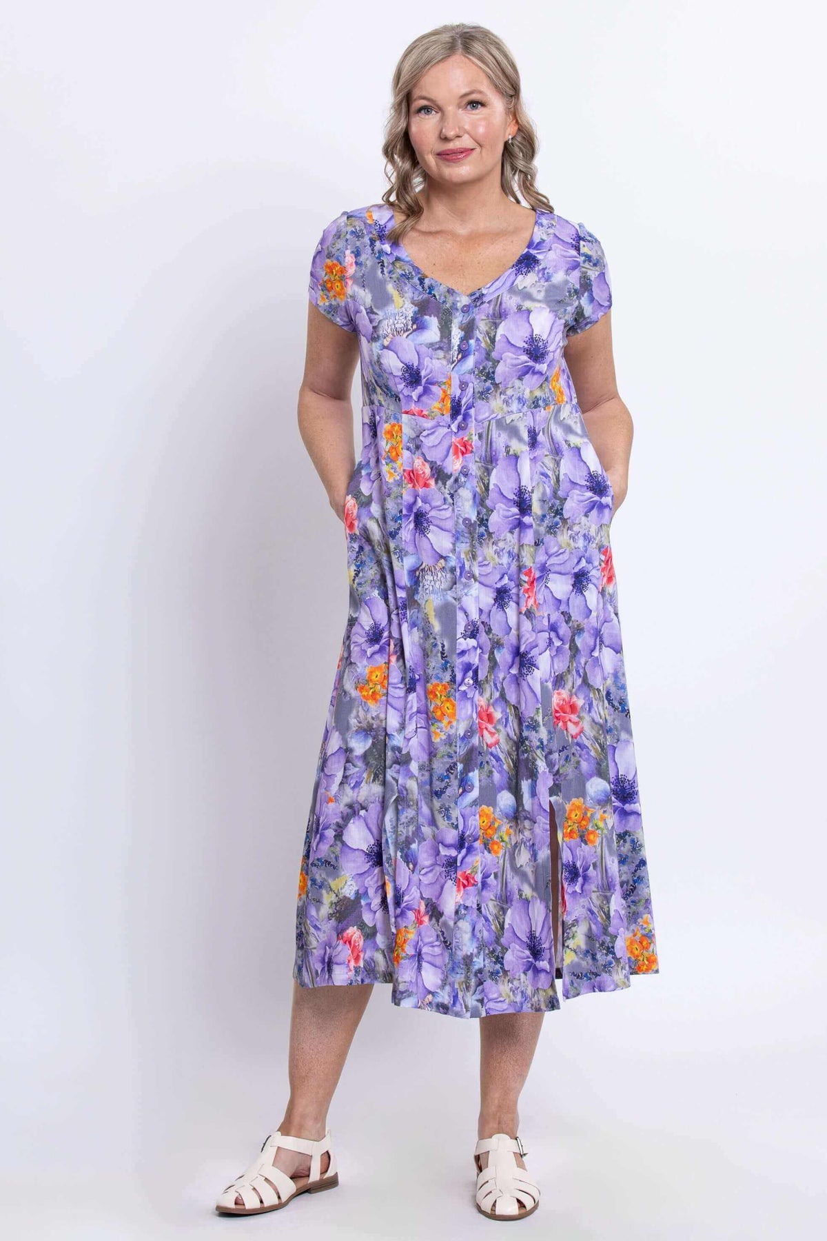 Woman standing in purple floral button-down dress with hands in side pockets