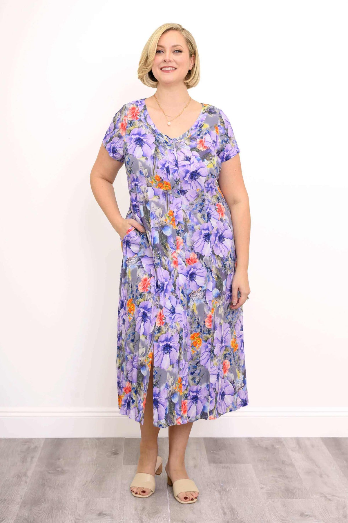 Woman wearing a purple floral short sleeve dress with side slits and pockets
