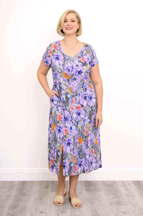 Woman wearing a purple floral short sleeve dress with side slits and pockets