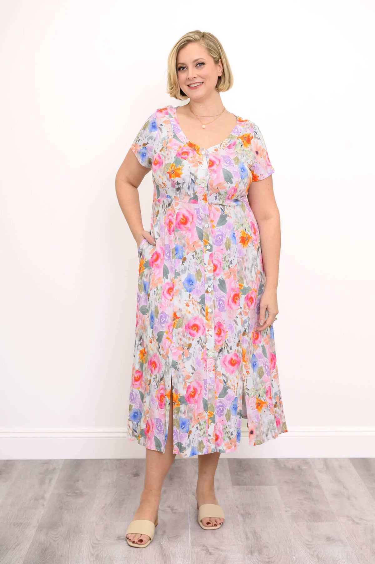 Model showcasing the floral dress with one hand in pocket