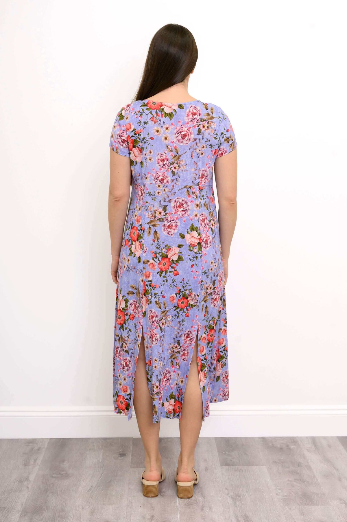 Back view of woman wearing short sleeve lilac floral patterned maxi dress with sandals
