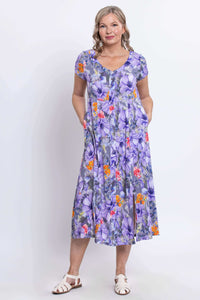 Full body front view of woman smiling in v-neck purple floral long dress with white sandals