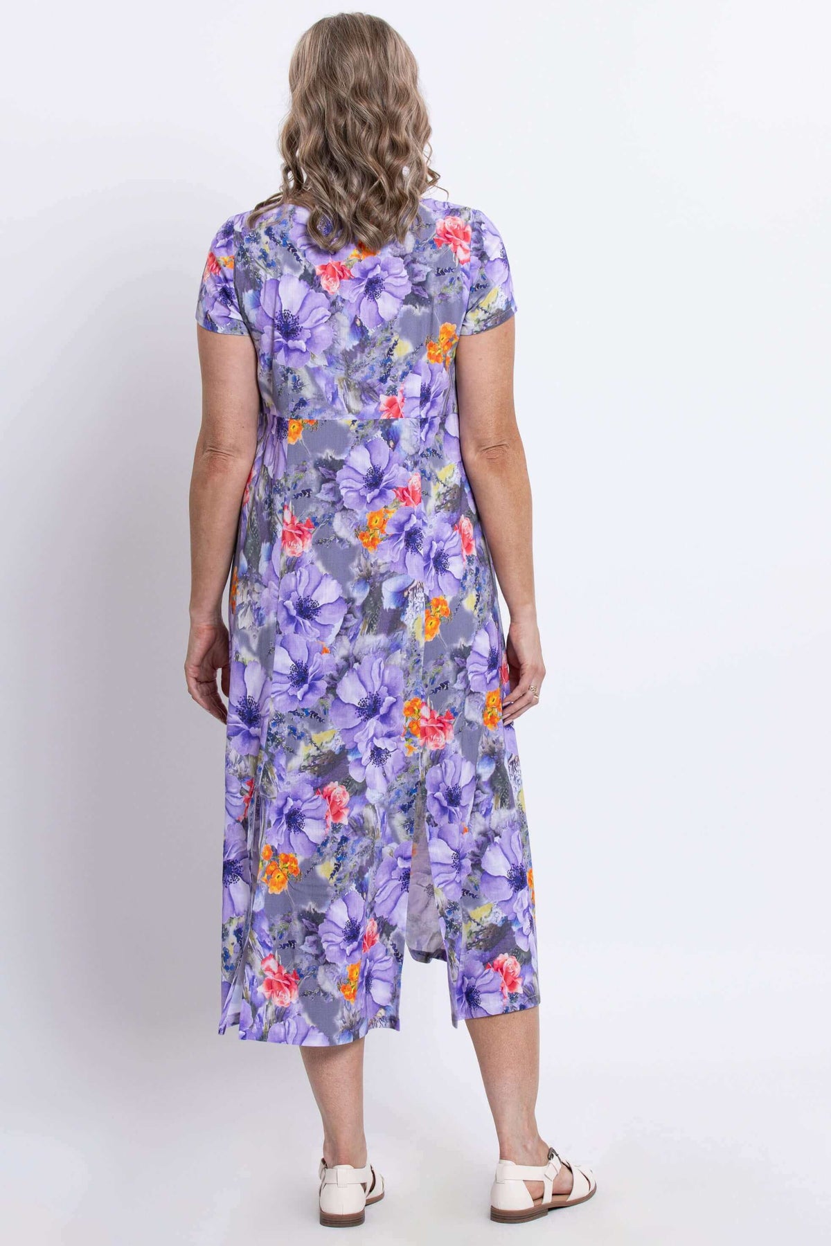 Back view of a woman wearing a purple floral print dress with back slit