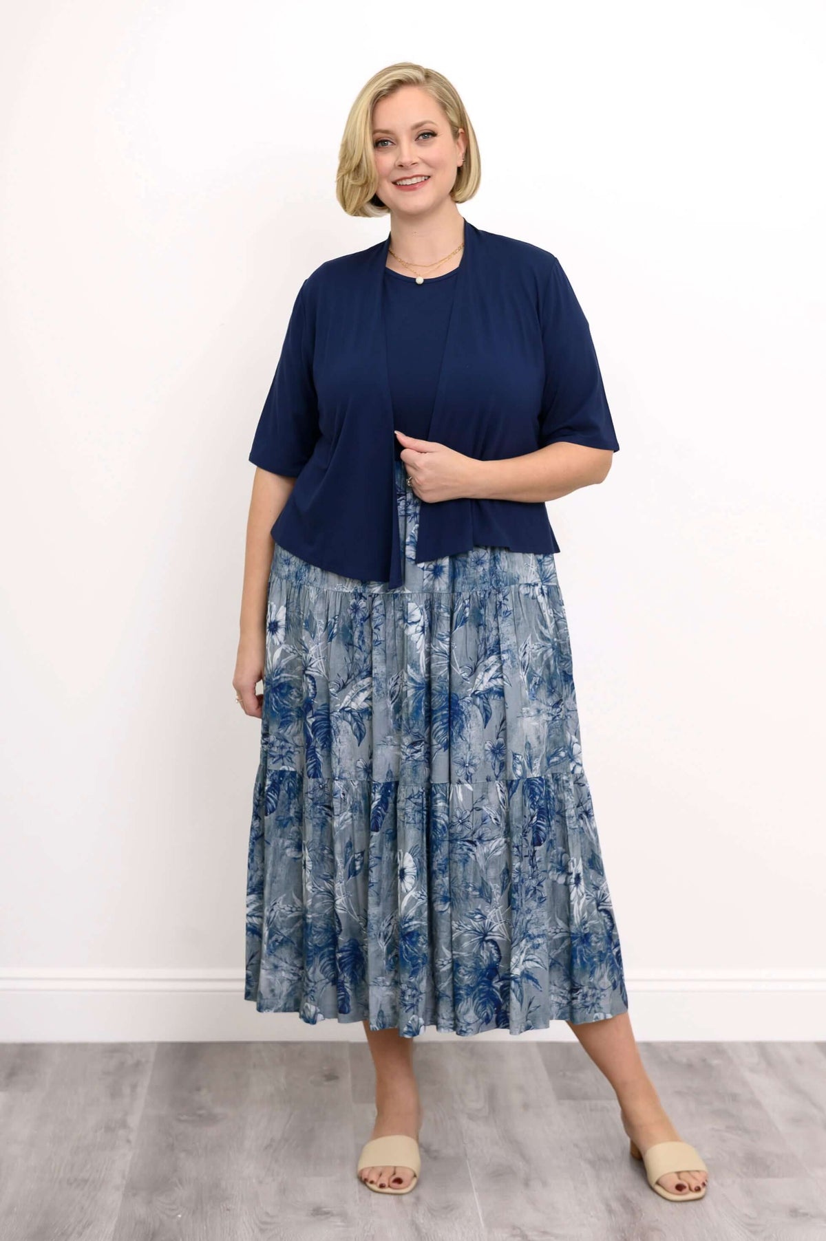 Woman in a navy and blue floral print midi dress styled with a navy short-sleeve cardigan