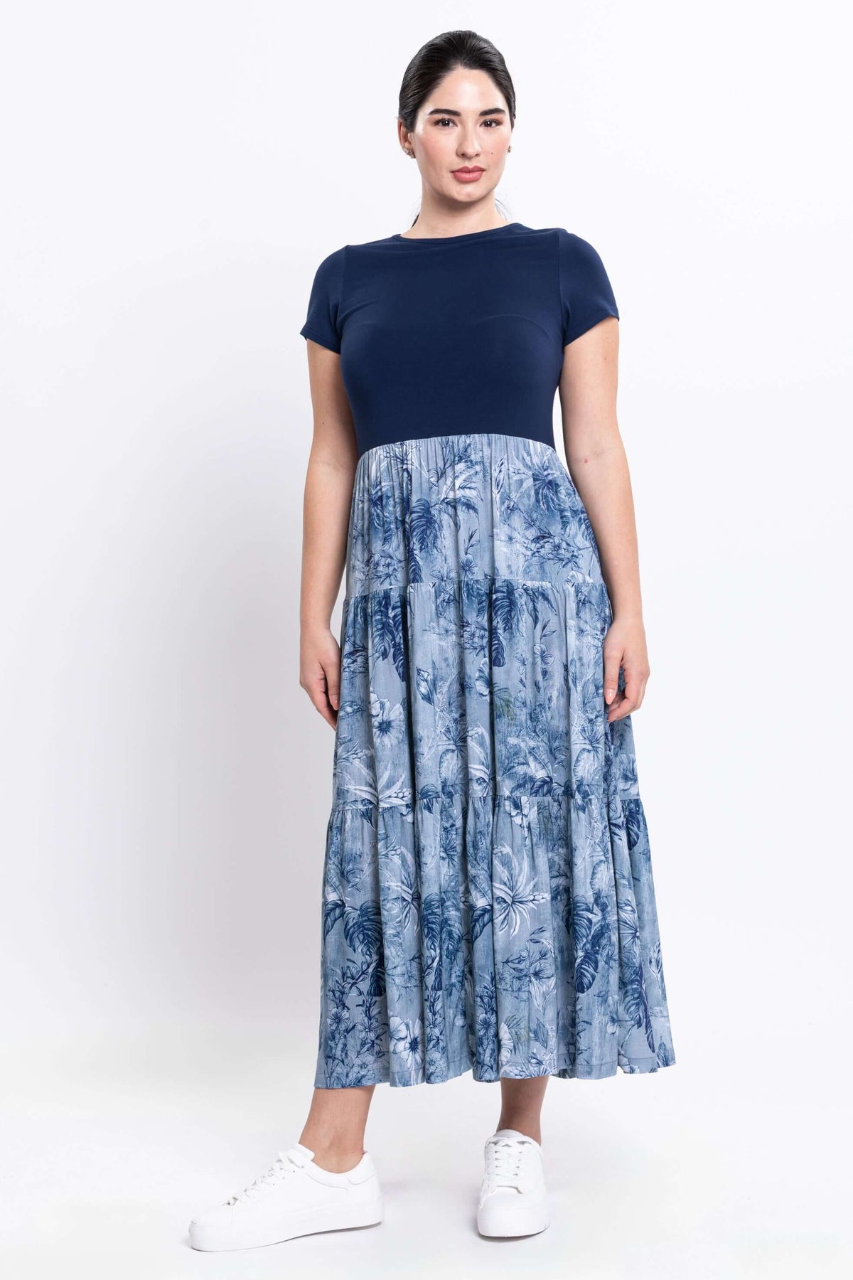 Woman modeling a navy and blue floral print midi dress with white sneakers