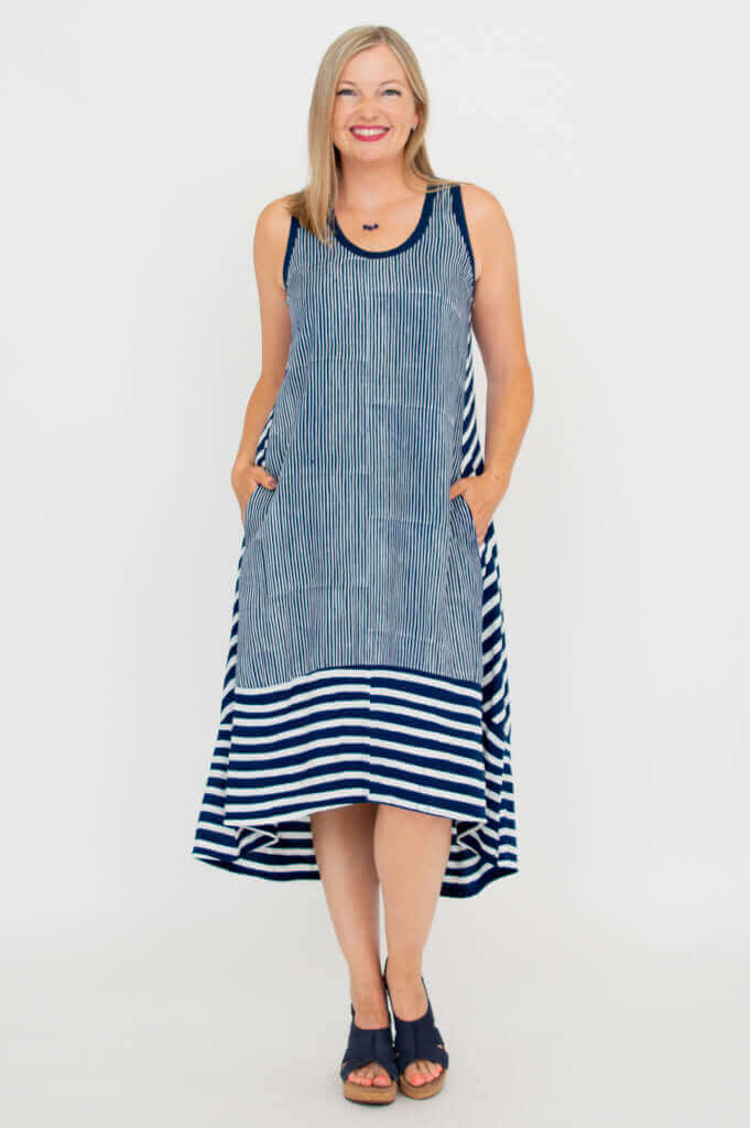 Woman wearing a sleeveless navy and white striped hi-lo summer dress, front view