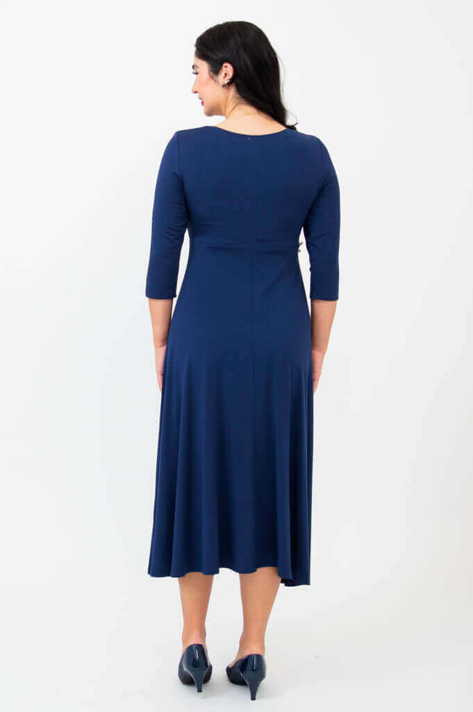 Woman showing the back view of a navy blue midi dress, standing pose