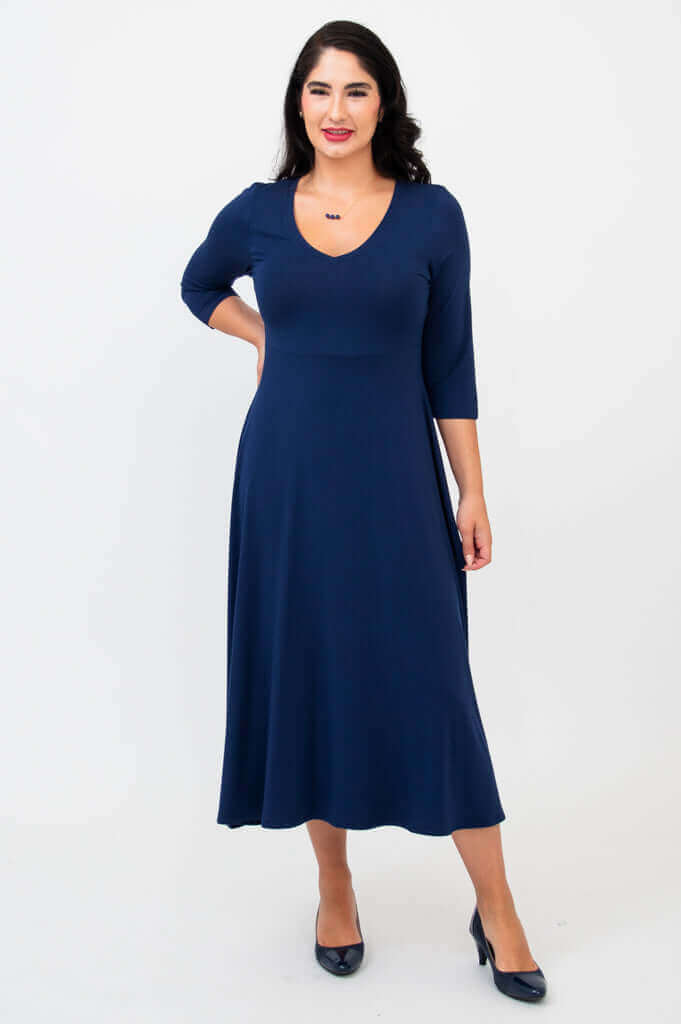 Woman posing in a navy blue midi dress with v-neckline, front view