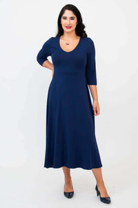 Woman posing in a navy blue midi dress with v-neckline, front view