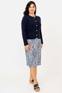Three-quarter view of woman modeling navy cardigan, paisley skirt, and sandals
