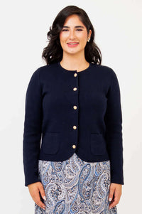 Front view of woman wearing a navy cardigan with gold buttons and front pockets