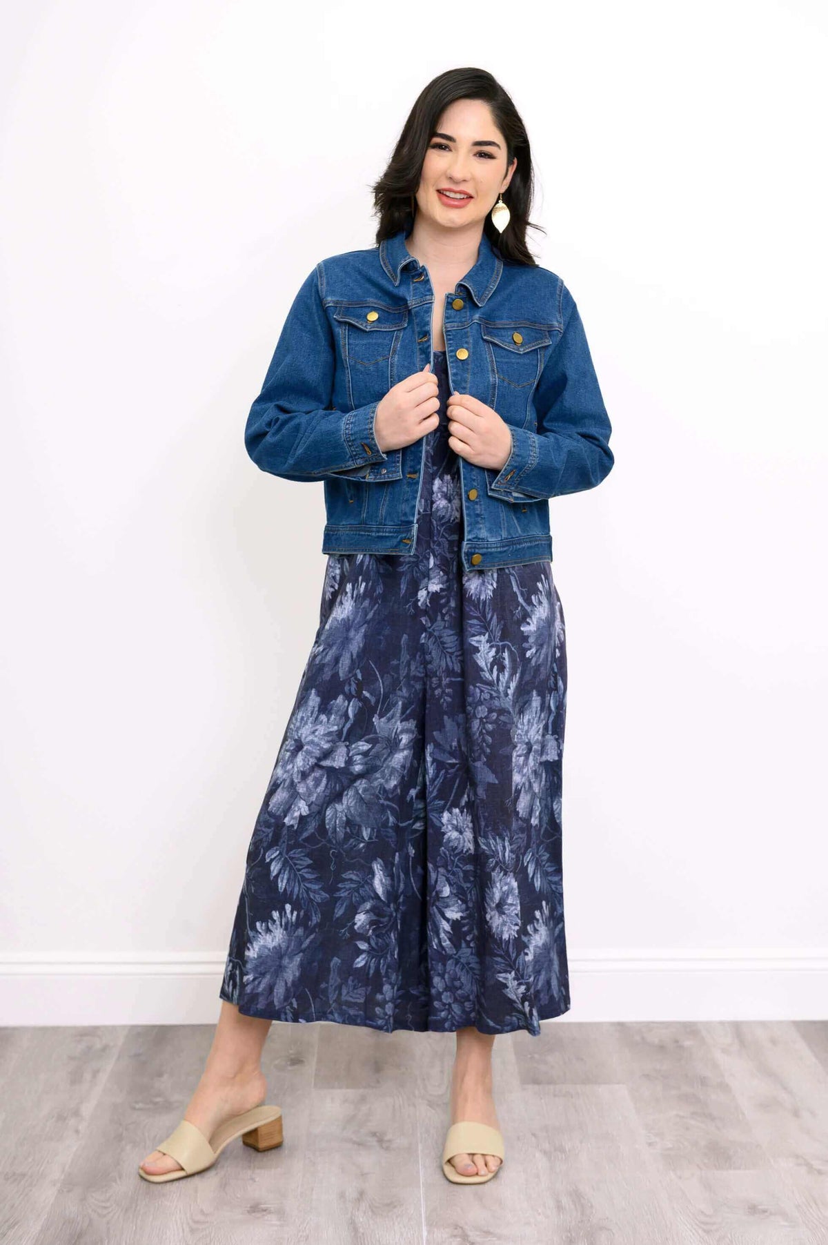 Woman wearing navy floral jumpsuit styled with denim jacket