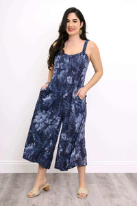 Woman modeling navy floral jumpsuit with hands in pockets