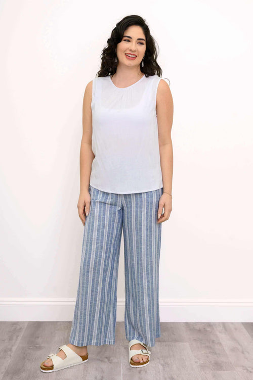 Full body front view of woman wearing white tank with pleated detail and blue stripe pants