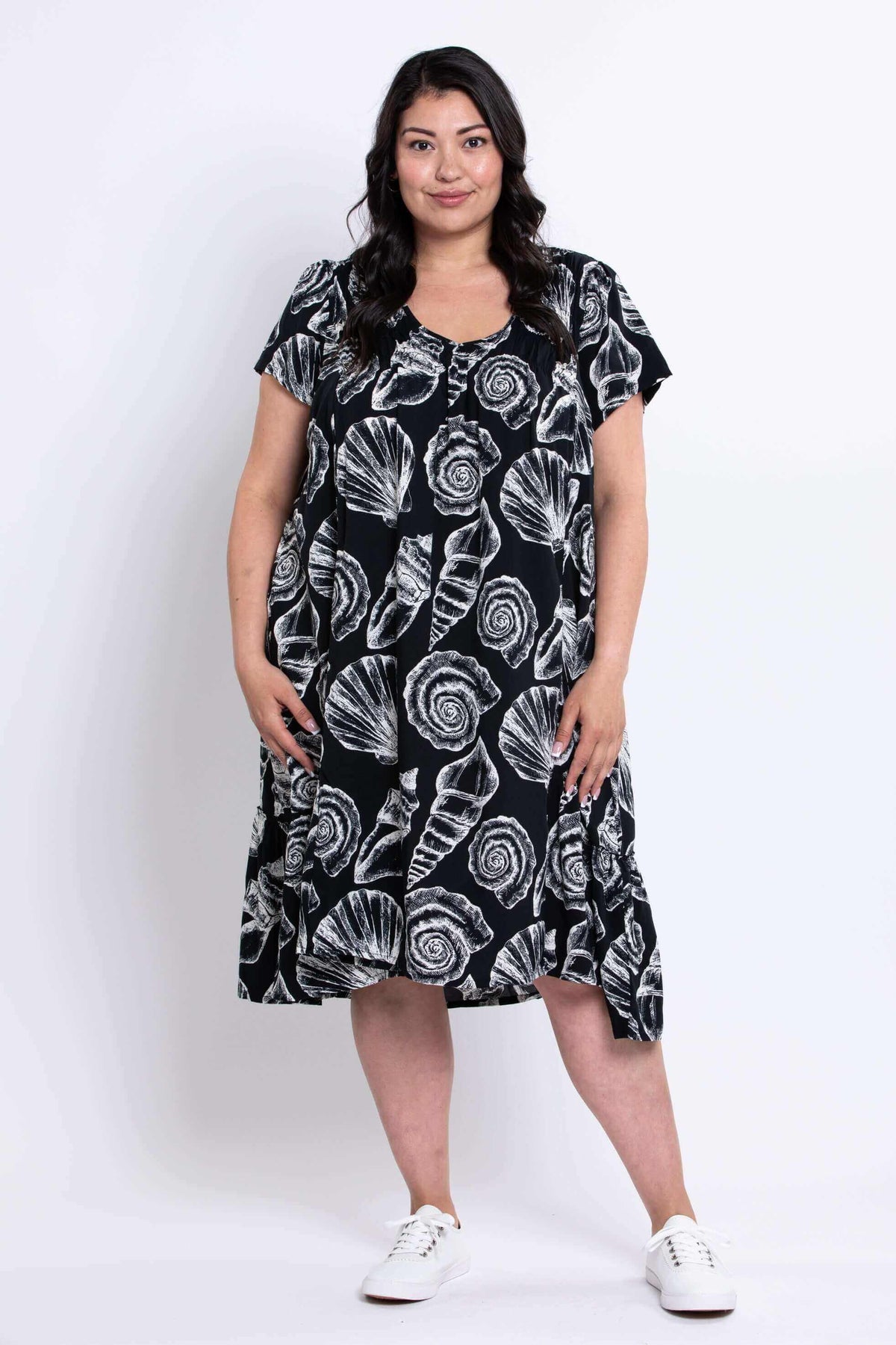 Front view of model wearing black Noosa Dress with white shell print and short sleeves
