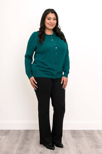 Full length view of a woman wearing a teal green cotton viscose cardigan sweater and black pants.
