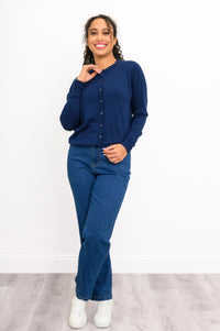 Front view of a woman wearing a navy crewneck button up cardigan styled with blue denim jeans.