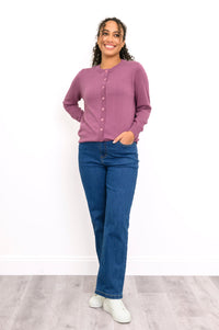 Front view of a woman wearing a pink crewneck button up cardigan styled with dark wash denim pants.