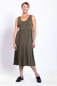 Woman wearing an olive empire waist midi dress and black shoes, smiling