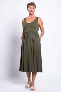 Woman showing pockets of olive empire waist midi dress with light sandals