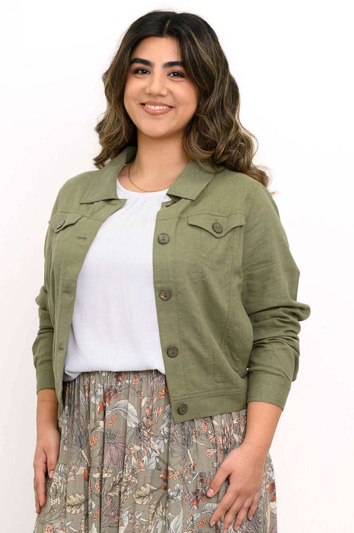 Woman wearing an olive green linen blend jacket over a white top and floral skirt