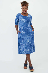 Woman wearing Olivia dress in blue tie dye with hands in pockets, front view