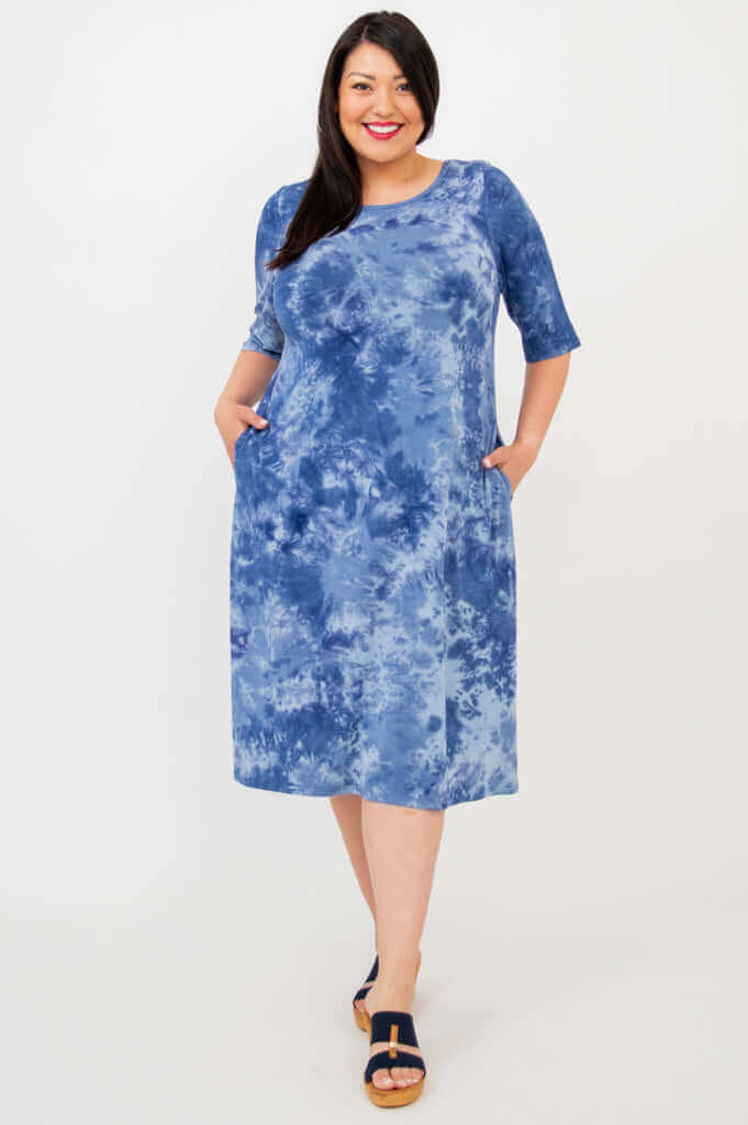 Plus size model in Olivia dress blue tie dye with hands in pockets, front view