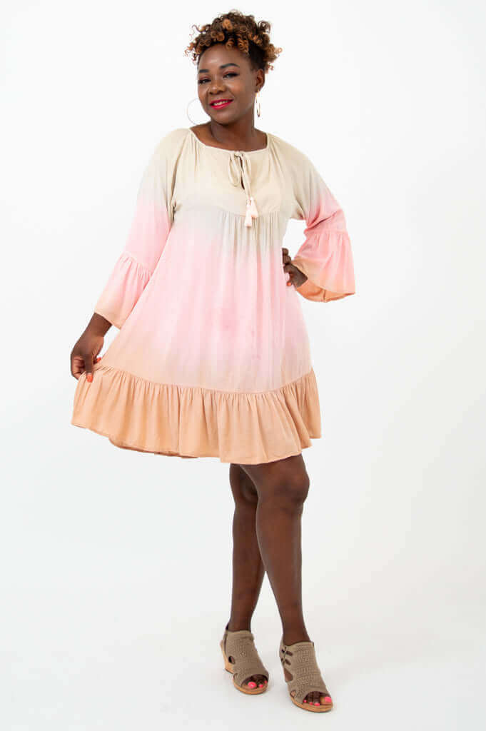 Woman wearing a ruffled hem ombre dress, posing with arm extended